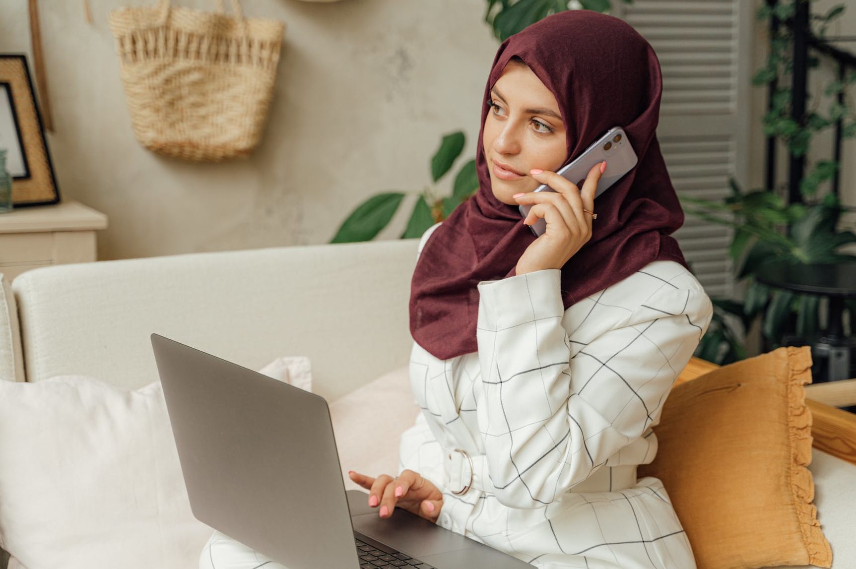 woman in a hijab using a laptop and a smartphone